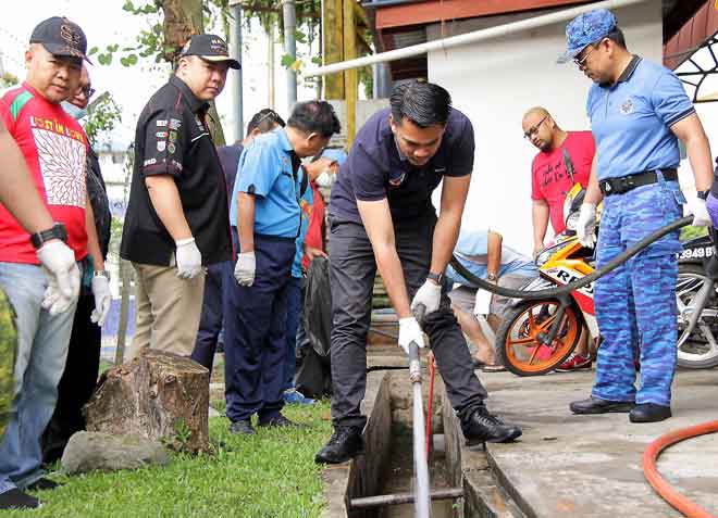 GOTONG-ROYONG Mohd Azis turut serta membersihkan longkang Pasar Pekan Manggatal semalam. — Gambar Bernama