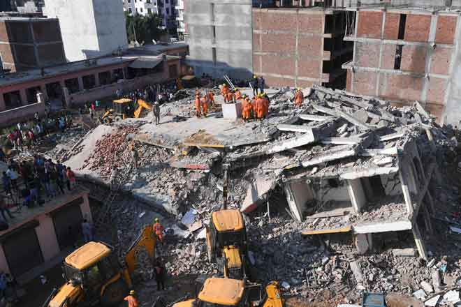  Anggota Pasukan Respons Bencana Kebangsaan (NDRF) menggeledah runtuhan untuk mencari mangsa terselamat  selepas sebuah bangunan yang sedang dibina roboh di atas sebuah kompleks perumahan di kampung Shah Beri di Greater Noida, di Uttar Pradesh semalam. — Gambar AFP