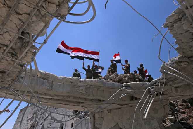  Tentera kerajaan Syria mengayunkan bendera kebangsaan mereka selepas menawan semula bandar Quneitra daripada pemberontak kelmarin. — Gambar AFP
