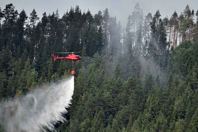  Helikopter mencurahkan air ke atas kebakaran hutan dekat kampung Grotingen di tengah Sweden. — Gambar Reuters