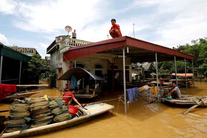  Seorang lelaki duduk di atas bumbung rumahnya selepas banjir melanda wilayah Ninh Binh kelmarin. — Gambar Reuters 