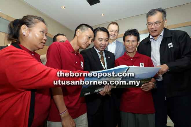  Hamden (tengah) melihat kandungan buku mengenai Kuba’an-Puak yang dilancarkan semalam. Turut kelihatan Henry (kanan) serta tiga orang komuniti Penan (dari kiri) Cherry Gadung, Jeffrey Moyong dan Asai Barat. — Gambar Chimon Upon 