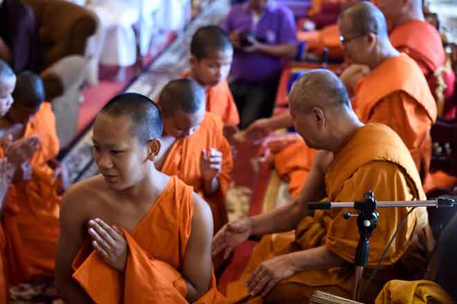  Jubah anggota pasukan bola sepak ‘Wild Boars’ ditanggalkan secara simbolik oleh sami Buddha dalam satu upacara untuk menandakan berakhirnya pemukiman pemain tersebut sebagai sami novis di tokong Wat Phra That Doi Tun. — Gambar AFP