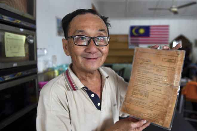  Tan Yong Min, 61, atau lebih mesra dengan panggilan ‘Ameng’ menunjukkan lesen perniagaan berusia 65 tahun di kedainya iaitu Kopitiam Kampung Parit, Negeri Sembilan. — Gambar Bernama