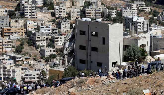  Pasukan keselamatan berkumpul dengan bangunan separuh ranap yang menjadi sarang persembunyian suspek di Salt, semalam. — Gambar Reuters