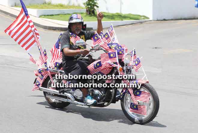  Azahari bersama motosikalnya yang dihias Jalur Gemilang mengelilingi bandar raya Kuching sehingga ke Santubong.
