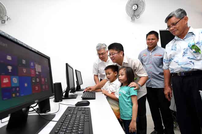  Ewon (dua kiri) menunjukkan cara menggunakan komputer kepada dua pengguna cilik selepas merasmikan Pusat e-Desa Kampung Baba, Telupid semalam.