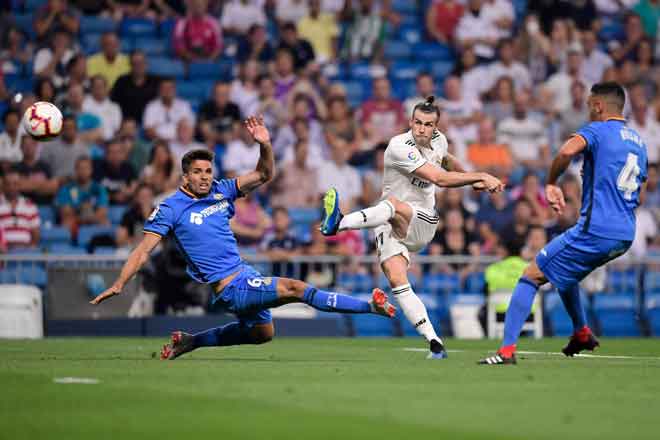  Bale (tengah) melepaskan rembatan melepasi kekangan dua pemain pertahanan Getafe ketika beraksi pada perlawanan La Liga Sepanyol di Stadium Santiago Bernabeu, Madrid Ahad lepas. — Gambar AFP