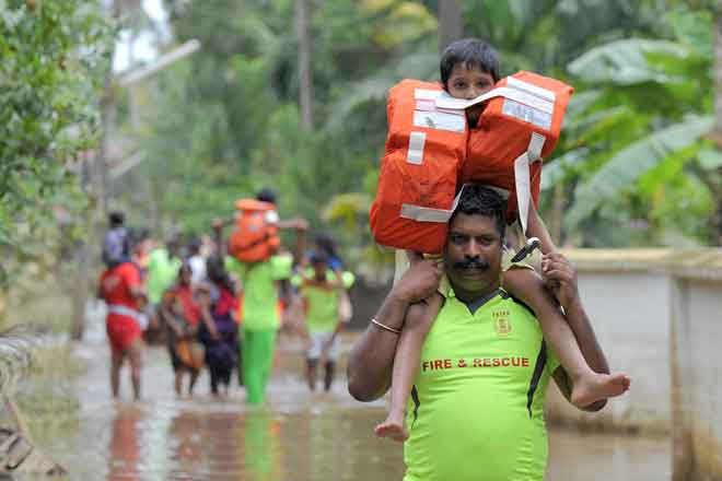  Anggota bomba dan penyelamat Kerala memikul kanak-kanak mengharungi air banjir                                                                                              semasa operasi menyelamat di kampung Annamanada di Daerah Thrissur, di negeri Kerala,                       selatan India kelmarin. — Gambar Manjunath Kiran/AFP