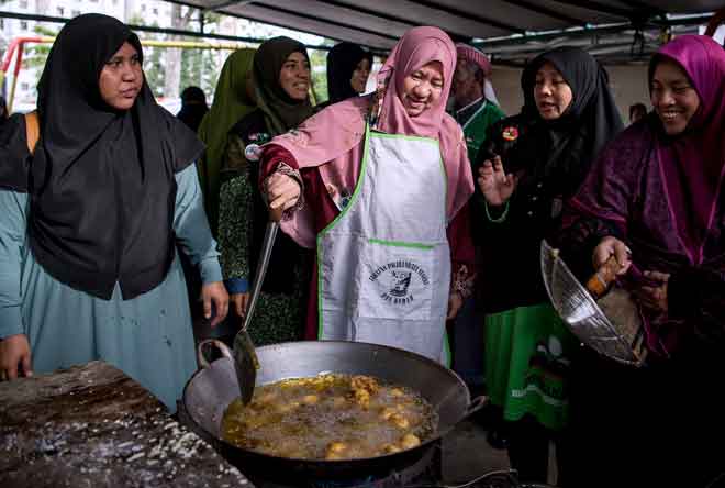  Halimah (tengah) melakukan demonstrasi masakan ketika berkempen dengan penduduk setempat pada Program ‘Jom Makan Buah- Buahan Tempatan’ di Padang PPRT Lembah Subang dekat Subang, semalam. — Gambar Bernama