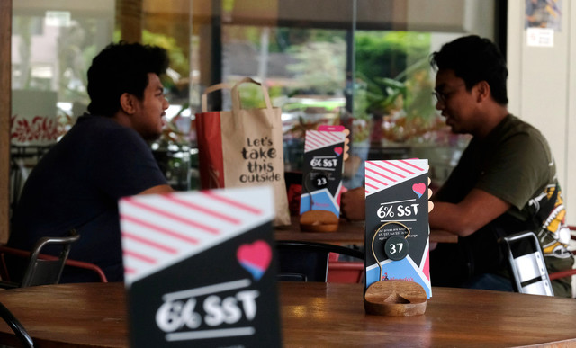 Sebuah restoran makanan meletakkan iklan SST bagi mengumumkan pelanggan bermulanya sistem cukai SST ketika tinjauan di Kuantan hari ini. - Gambar Bernama 