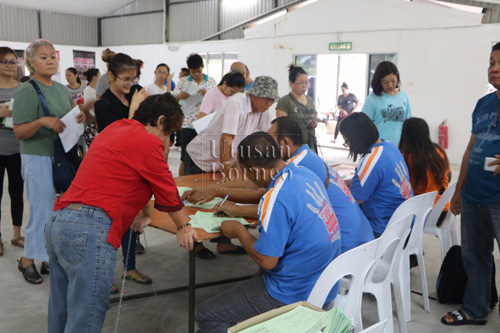 Pemilik anjing beratur sementara menunggu giliran untuk mendapatkan vaksin anti rabies percuma.