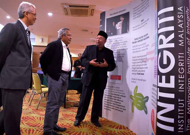  Muhammad Safian (tengah) mendengar penerangan daripada Hamilye (kanan) ketika melawat pameran selepas merasmikan Seminar Pemerkasaan Integriti Negeri Pahang, Kuantan semalam. — Gambar Bernama