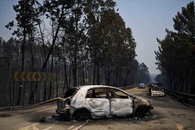  Foto fail yang diambil pada 18 Jun 2017 ini menunjukkan kereta terbakar di sebatang jalan selepas kebakaran belantara berlaku di Figueiro dos Vinhos, Portugal. — Gambar AFP