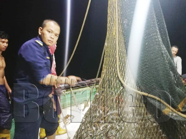 ANGGOTA APMM menunjukkan hasil tangkapan di dalam bot nelayan tempatan yang ditahan pasukan penguatkuasa APMM dalam Ops Khas.