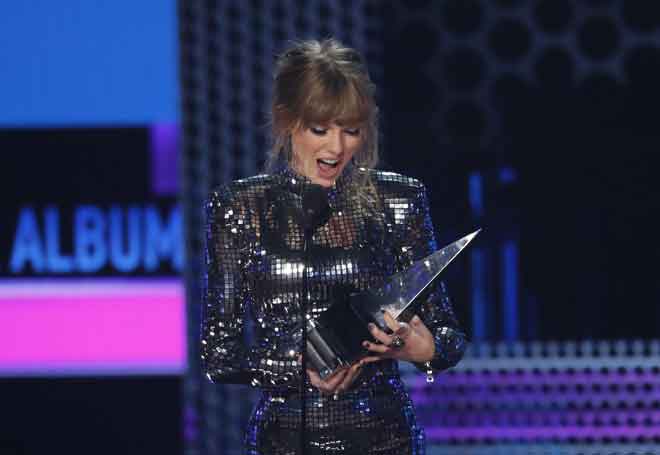  Taylor Swift melihat trofi ‘Album - Pop/Rock’ yang dimenanginya semasa Anugerah Muzik Amerika 2018 di Los Angeles, California baru-baru ini. — Gambar Reuters