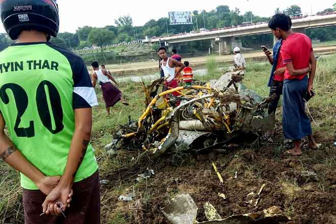  Orang ramai melihat bahagian yang tertanggal daripada jet tentera yang terhempas di sebuah padang di Magway semalam. — Gambar AFP