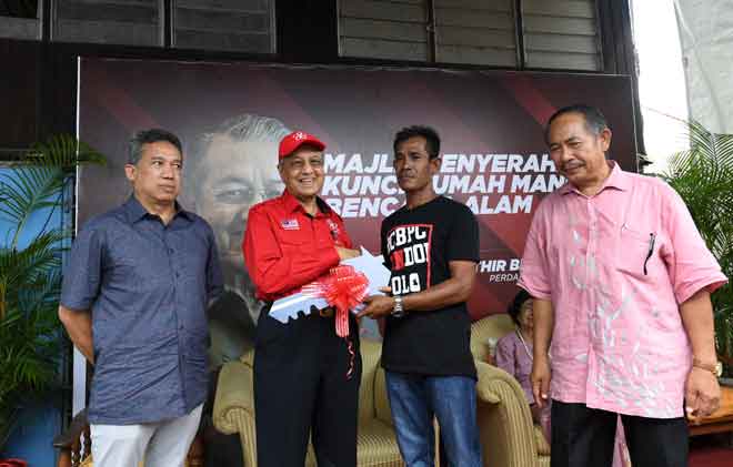  Dr Mahathir menyampaikan replika kunci rumah kepada Zamri Mohd  Akhir (dua kanan) pada majlis penyampaian kunci rumah kepada mangsa bencana ribut di Kampung Kuala Teriang, Langkawi, dekat Langkawi, semalam. — Gambar Bernama