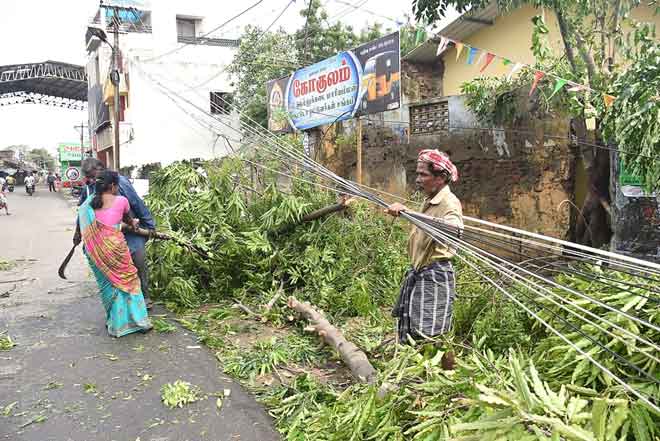  Penduduk India mengalih pokok tumbang berhampiran stesen kereta api di Nagapattinam dalam negeri                         Tamil Nadu, selatan India, semalam selepas Siklon Gaja melanda wilayah tersebut. — Gambar AFP