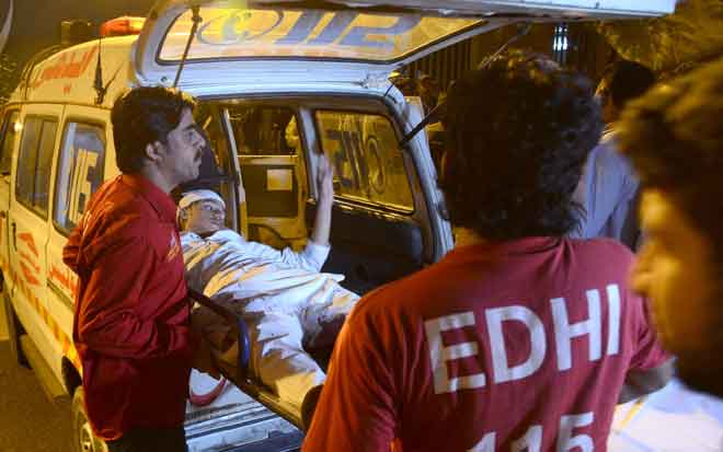  Dalam gambar yang diambil kelmarin, pekerja ambulans sukarelawan Pakistan membawa seorang mangsa letupan yang cedera ke hospital di Karachi. — Gambar AFP 