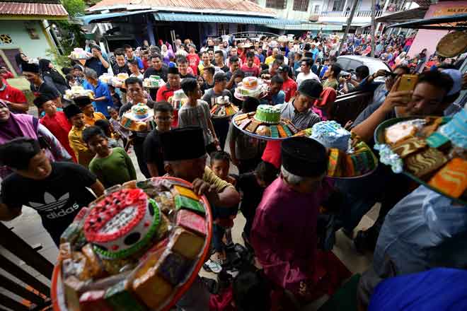  Penduduk kampung membawa talam berisi kek serta kuih-kuih asli di Masjid Bumiputera Kampung Sebandi Ulu sempena sambutan Maulidur Rasul. — Gambar Bernama