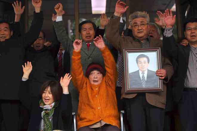  Kim Sung-joo (duduk tengah), mangsa buruh paksaan tentera Jepun sewaktu penjajahannya di semenanjung Korea dari 1910 hingga 1945, dan saudara-mara mangsa lain             menunjukkan reaksi selepas keputusan dibaca di Mahkamah Agung di Seoul semalam. — Gambar AFP