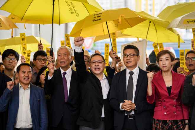  Dalam gambar yang diambil pada 19 November 2018,  Chu (dua kiri), Tai (tengah) dan Chan (dua kanan) serta aktivis prodemokrasi lain melaungkan slogan sebelum mereka memasuki Mahkamah Majistret Kowloon Barat di Hong Kong. — Gambar AFP