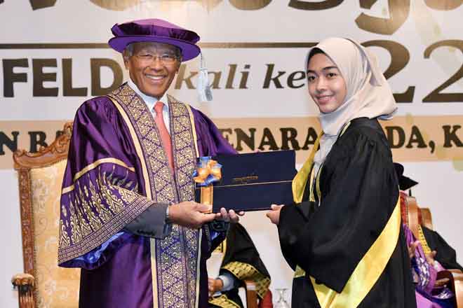  Megat Zaharuddin (kiri) menyampaikan sijil kepada pelajar cemerlang Nur Athira           Azeera Mamat di Menara FELDA di Kuala Lumpur semalam. — Gambar Bernama