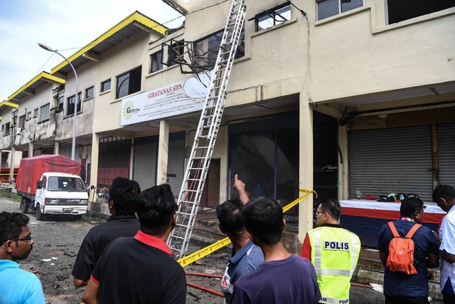 Orang ramai melihat keadaan kebakaran seunit rumah kedai dua tingkat