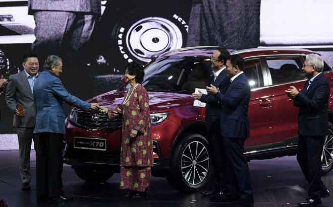  Tun Dr Mahathir menyerahkan kunci kereta kepada isterinya Tun Dr Siti Hasmah ketika melancarkan Proton SUV X70 di Pusat Konvensyen Kuala Lumpur, malam kelmarin. — Gambar Bernama