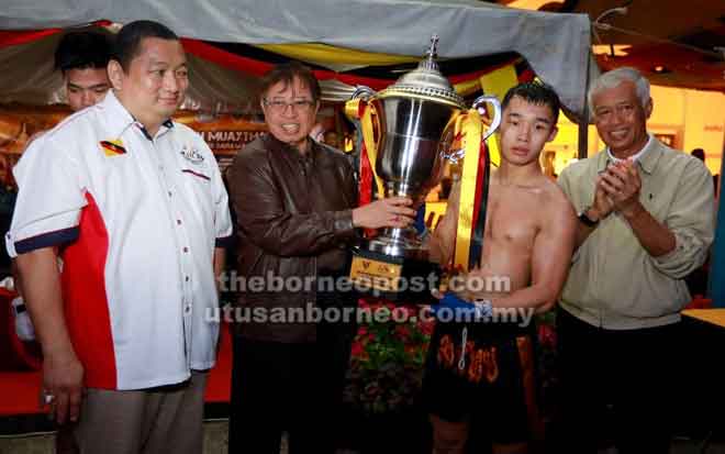  Abang Johari menyampaikan Piala Ketua Menteri Sarawak kepada Morris pada Kejohanan Muaythai Sarawak di Kuching, malam kelmarin. Turut kelihatan, Abang Abdul Wahap dan Jumaat (kiri).