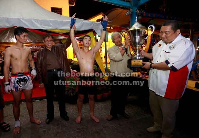  Abang Johari ngangkatka jari Morris lebuh dipadu menggi gelar champion Pekit Muaythai Sarawak ungkup Mangkuk Kepala Menteri Sarawak, malam kemari.