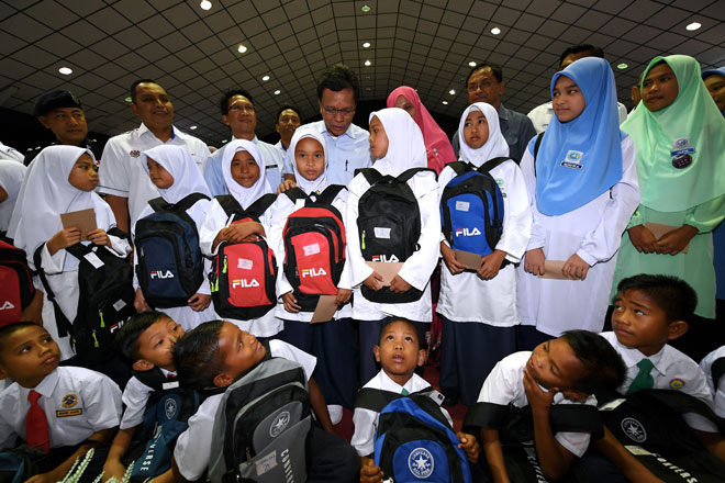  Mohd Shafie (tengah) beramah mesra dengan sebahagian murid-murid selepas menyampaikan bantuan persekolahan pada majlis Kembali Ke Sekolah di Dewan Masyarakat Semporna semalam. — Gambar Bernama