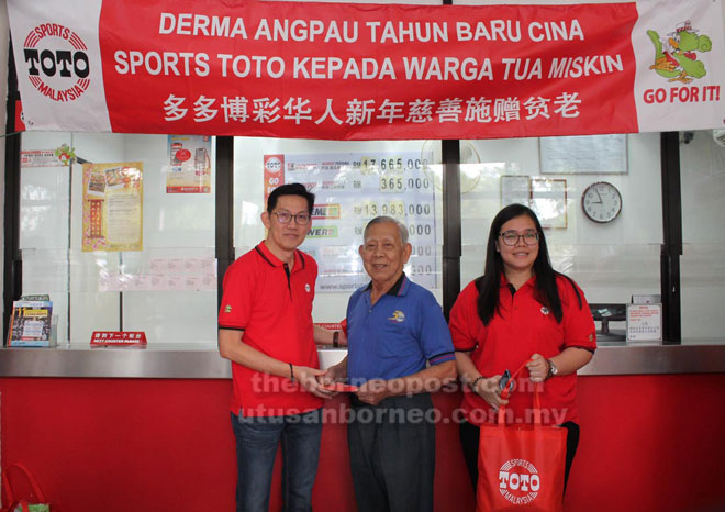  Tee (kiri) menyampaikan sumbangan angpau kepada salah seorang penerima di premis Sport Toto Taman Bumiko semalam.
