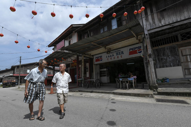  Warga emas berketurunan Cina Hainan, Kong Hin Eng, 89, (kanan) bersama rakannya Bo Chia Weng, 78, berjalan melintasi deretan rumah kedai yang masih beroperasi di Kampung Baru Ayer Jerneh, Kemasik di Kemaman, semalam. — Gambar Bernama