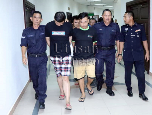 Teng (dua kiri) dan Tiong (tengah) serta empat lagi lelaki tempatan (sedikit terlindung di belakang) diiringi oleh anggota polis di Kompleks Mahkamah di sini, hari ini