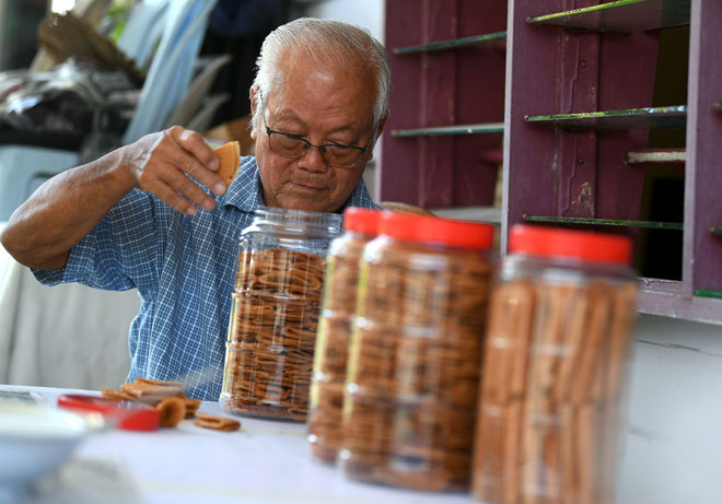  Choo memasukkan kuih kapit yang dibuat oleh anaknya Choo dan isteri, Fong dalam bekas ketika menyiapkan tempahan pelanggan. — Gambar Bernama