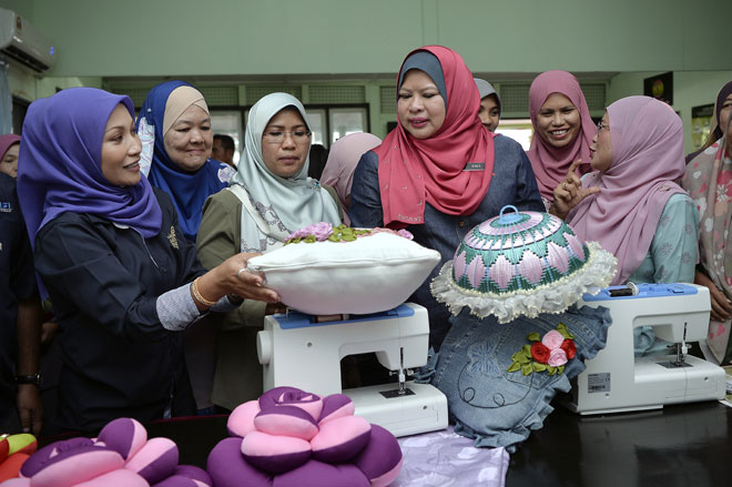  Rina (tiga kanan) diberi penerangan oleh pemilik Arina Fashion & Design Institute Asfarina Samion selaku pengendali kursus ‘Quick Win’ Seni Tangan Jahitan Kreatif KEMAS di Balai Raya Kampung Rincing Hilir sempena lawatan kerja ke Semenyih semalam. Turut kelihatan Timbalan Ketua Setiausaha Kementerian Pembangunan Luar Bandar Norison Ramli (tiga kiri). — Gambar Bernama