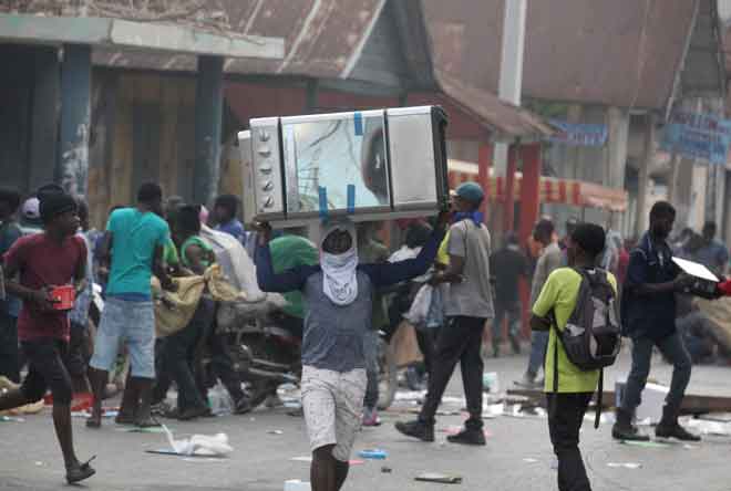  Perusuh menjarah sebuah kedai elektronik sewaktu protes antikerajaan di Port-au-Prince pada Selasa. — Gambar Reuters