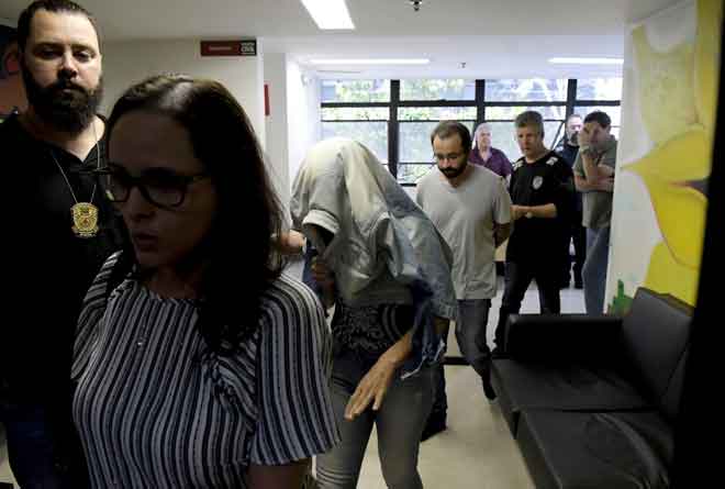  Pekerja syarikat perlombongan Vale SA yang dituduh oleh pendakwa negeri menyembunyikan kelemahan di sebuah empangan yang pecah, diiringi anggota polis di Belo Horizonte, Brazil kelmarin. — Gambar Reuters