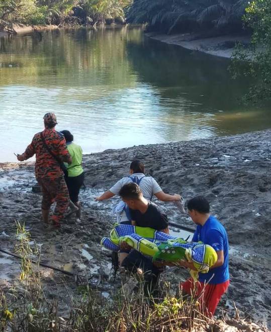 PENDUDUK kampung mengangkat kanak-kanak lelaki yang ditemukan lemas di Sg Muanad. 