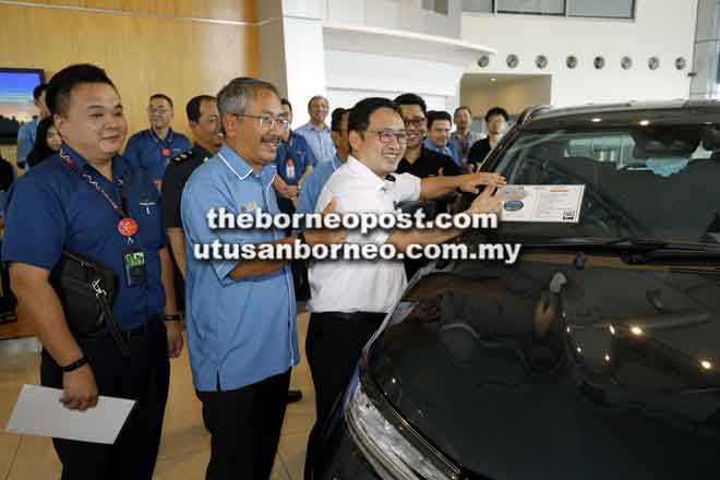  Chong ngelekatka label ASEAN NCAP ba chermin Perodua Aruz rambau pengawa di Kuching kemari. Bela dipeda(ari kiba) Desmond enggau Rostam.