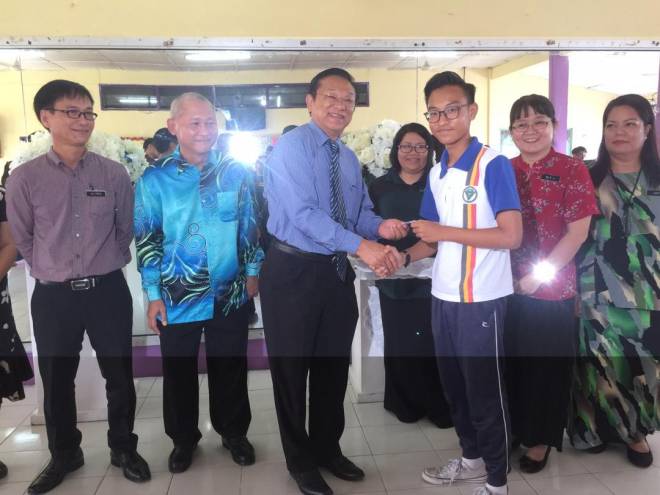  Dr Teo menyampaikan kupon kepada seorang pelajar SMKDP disaksikan guru dan ahli PIBG.