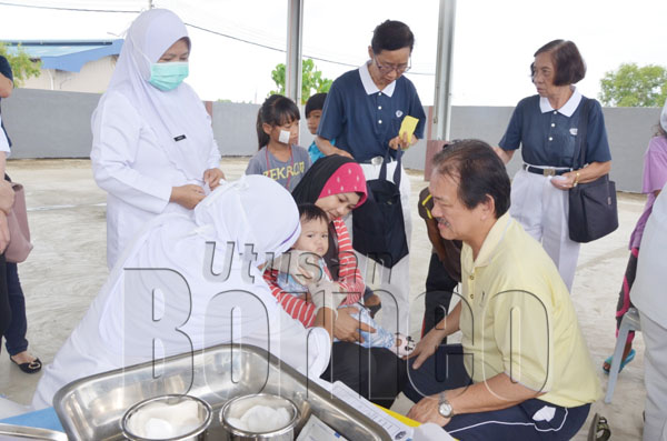 STEPHEN (kanan) meninjau proses suntikan vaksin kepada kanak-kanak di Kampung Mangkalinau.