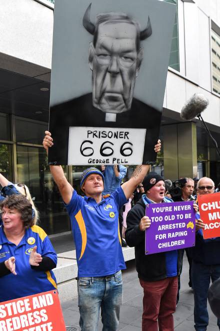  Penunjuk perasaan membawa plakad ketika berhimpun di luar Mahkamah Daerah untuk mendengar hukuman ke atas Pell di Melbourne, Australia pada Rabu. — Gambar AFP