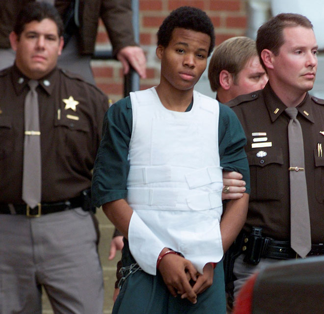  Malvo (tengah) diiringi keluar dari mahkamah juvana Fairfax County oleh Syerif Fairfax County pada 15 November 2002. — Gambar Reuters