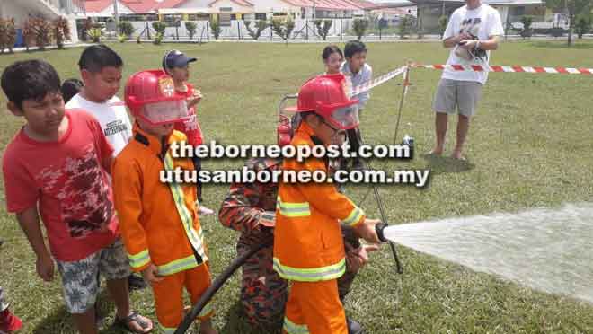  Pelajar Tenby berpeluang mencuba memadam api sambil dibantu anggota bomba.  