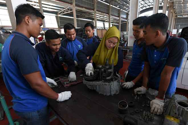  Nur Izzatie (tengah) bersama rakan memasang ‘gear box’ kenderaan ketika ditemui di Tesdec, Marang, kelmarin. — Gambar Bernama 