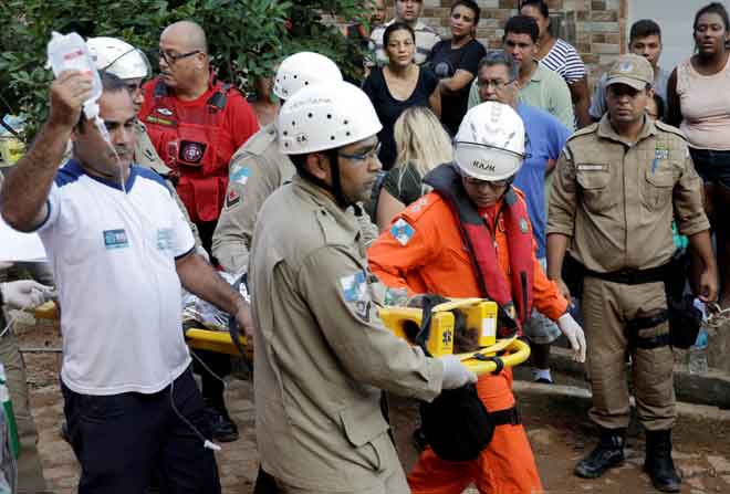 Seorang mangsa dibawa dengan pengusung selepas sebuah bangunan runtuh di kawasan setinggan Muzema, Rio de Janeiro, Brazil kelmarin. — Gambar Reuters