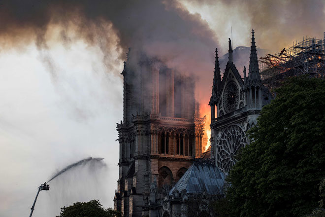  Anggota bomba memadamkan api yang berkepul-kepul dari bumbung Katedral Notre Dame di Paris pada Isnin. — Gambar AFP